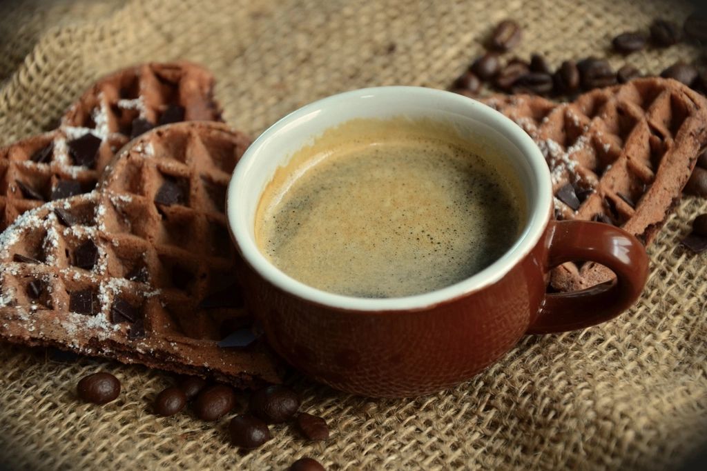 Taza de café acompañada de waffles dulces