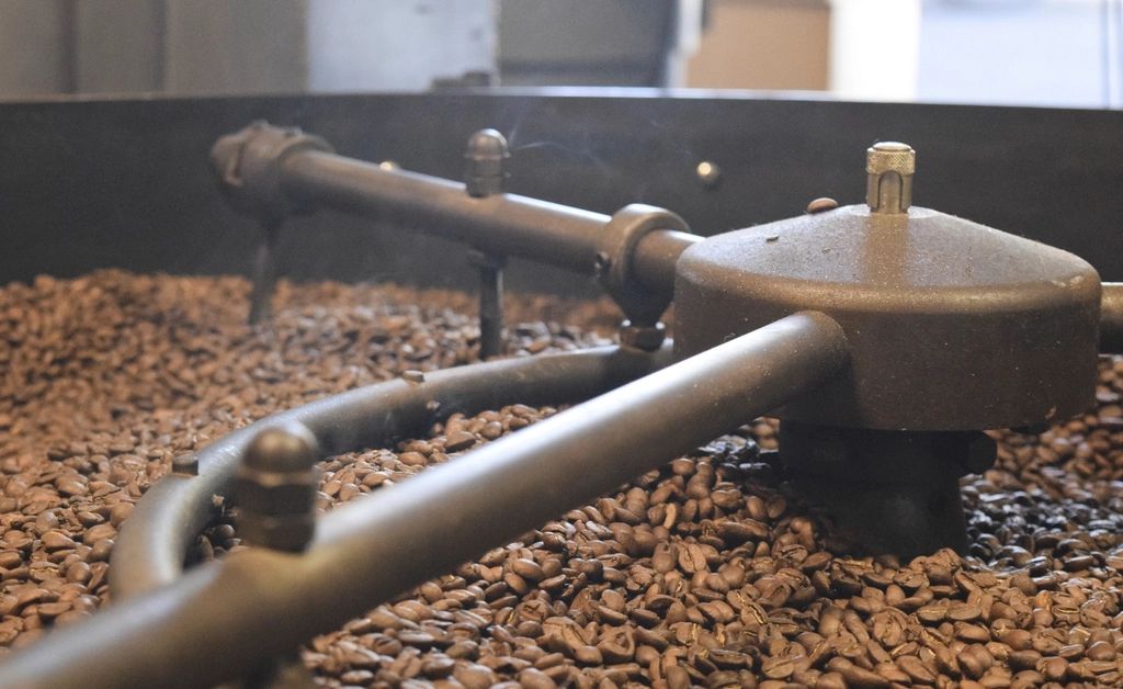 Granos de café recién tostados en la bandeja de enfriamiento de la tostadora